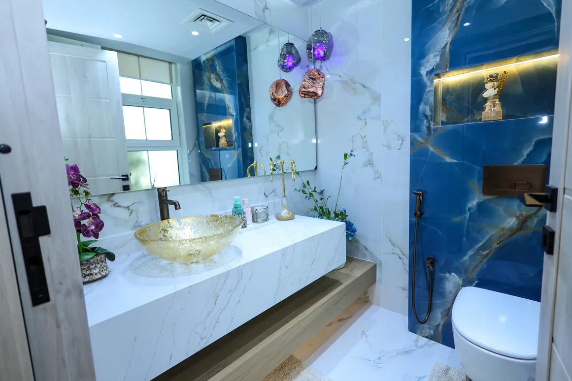 Mudon — Washbasin area with blue-toned wall finishes and illuminated niches
