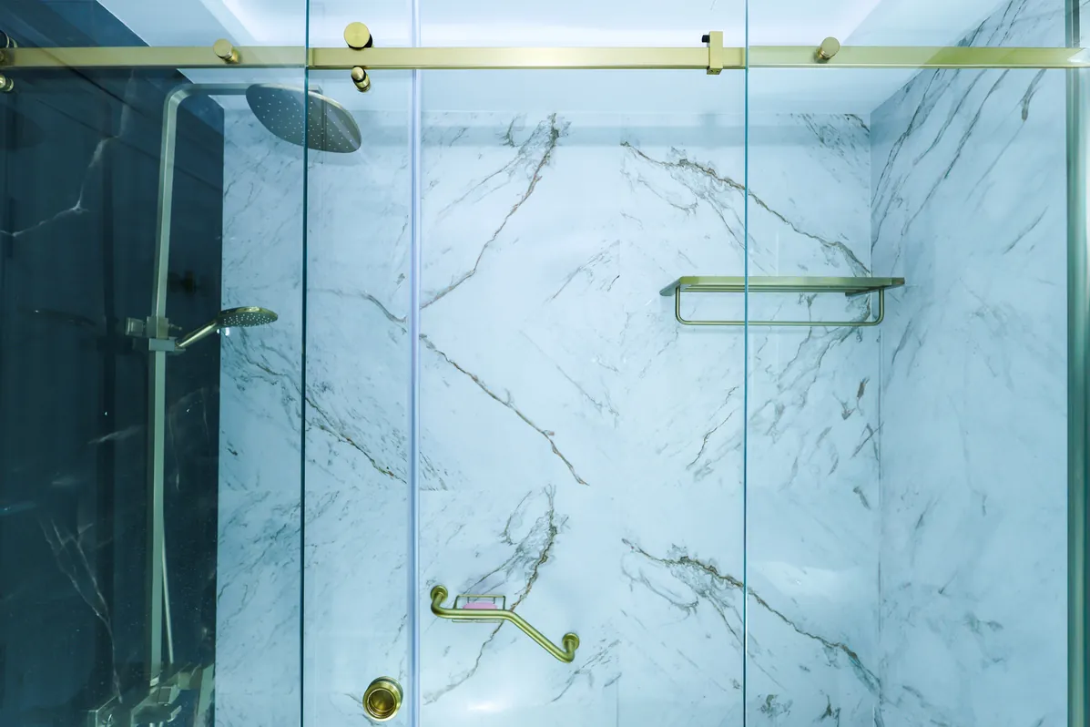 Mudon — Shower area with light stone-look walls and blue accent finishes