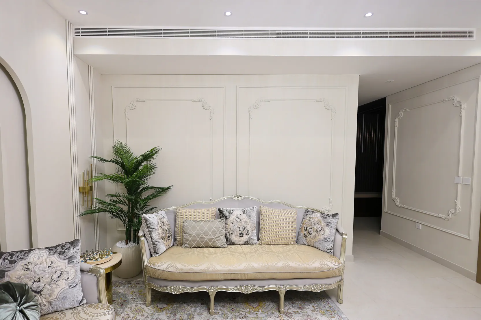 Tilal Al Furjan — Neutral sofa arrangement framed by decorative wall mouldings
