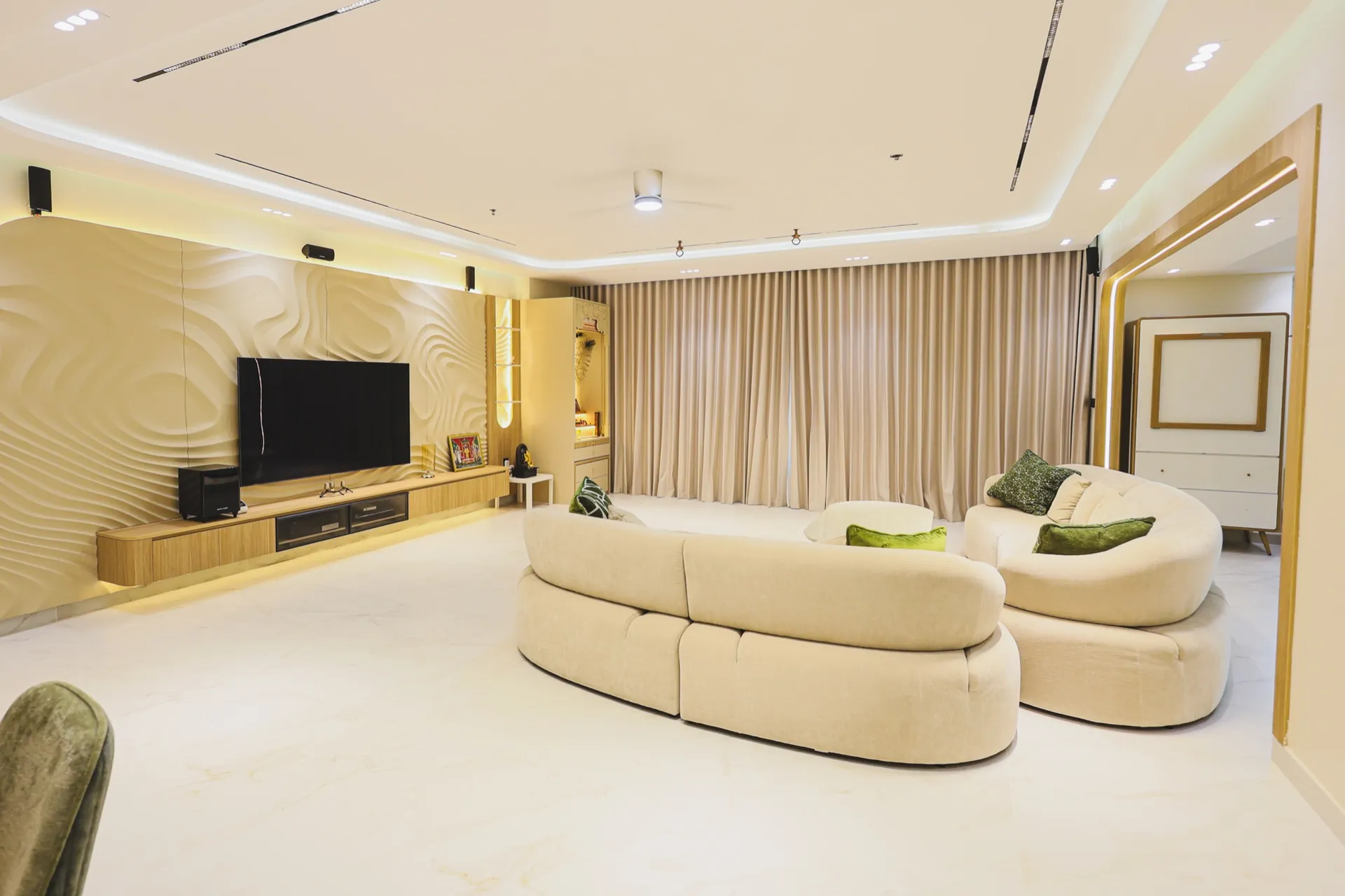 Living room with curved cream sofas, full-height curtains and warm ceiling lighting